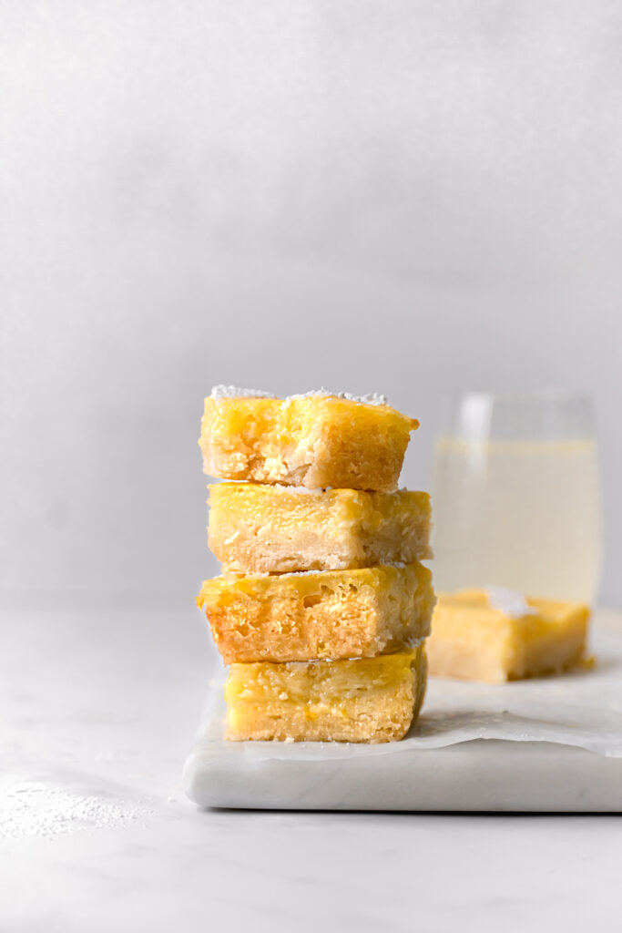 small batch lemon bars with an almond shortbread crust stacked up on square marble board