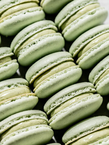 pistachio macarons lined up on baking sheet.