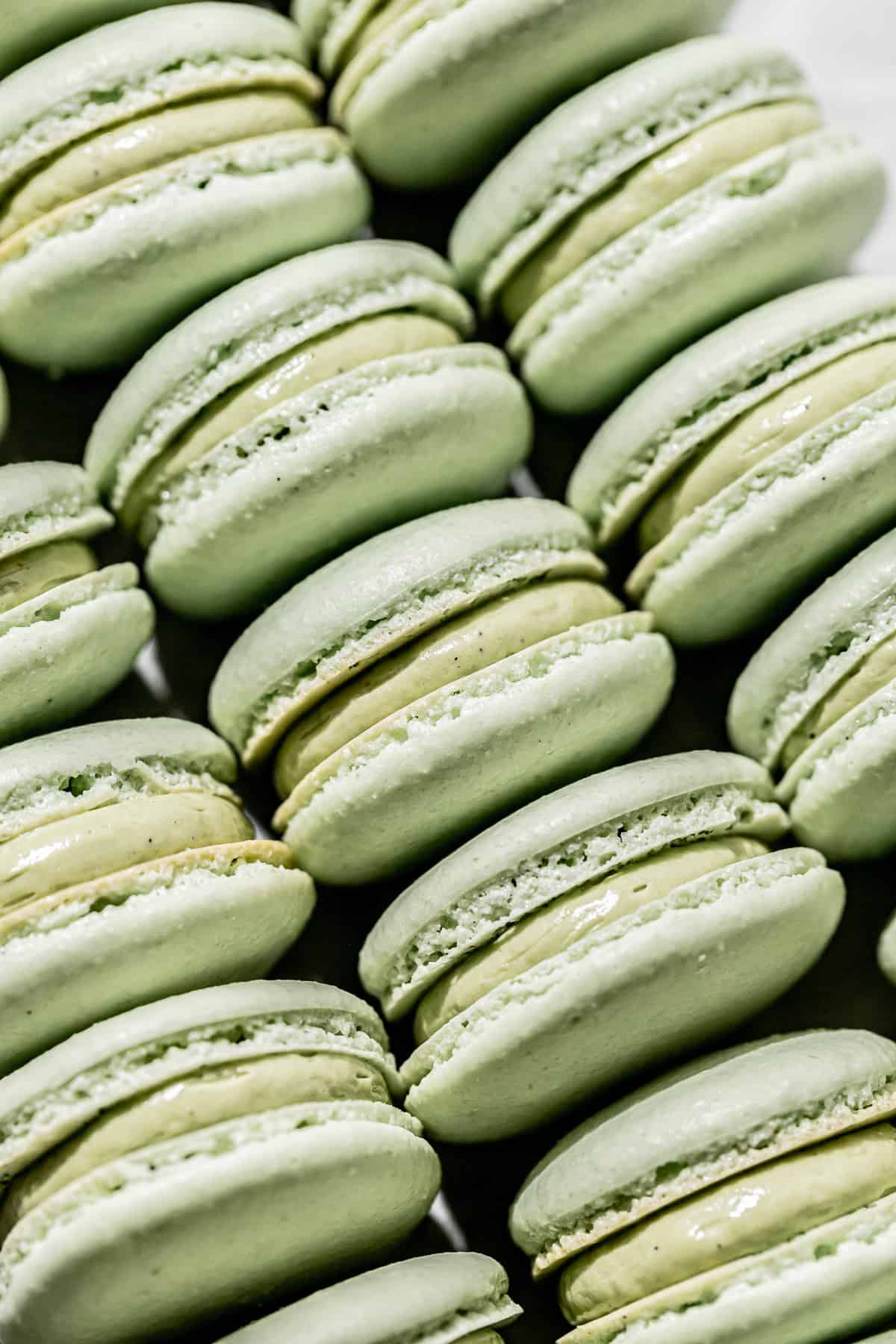 pistachio macarons lined up on baking sheet.