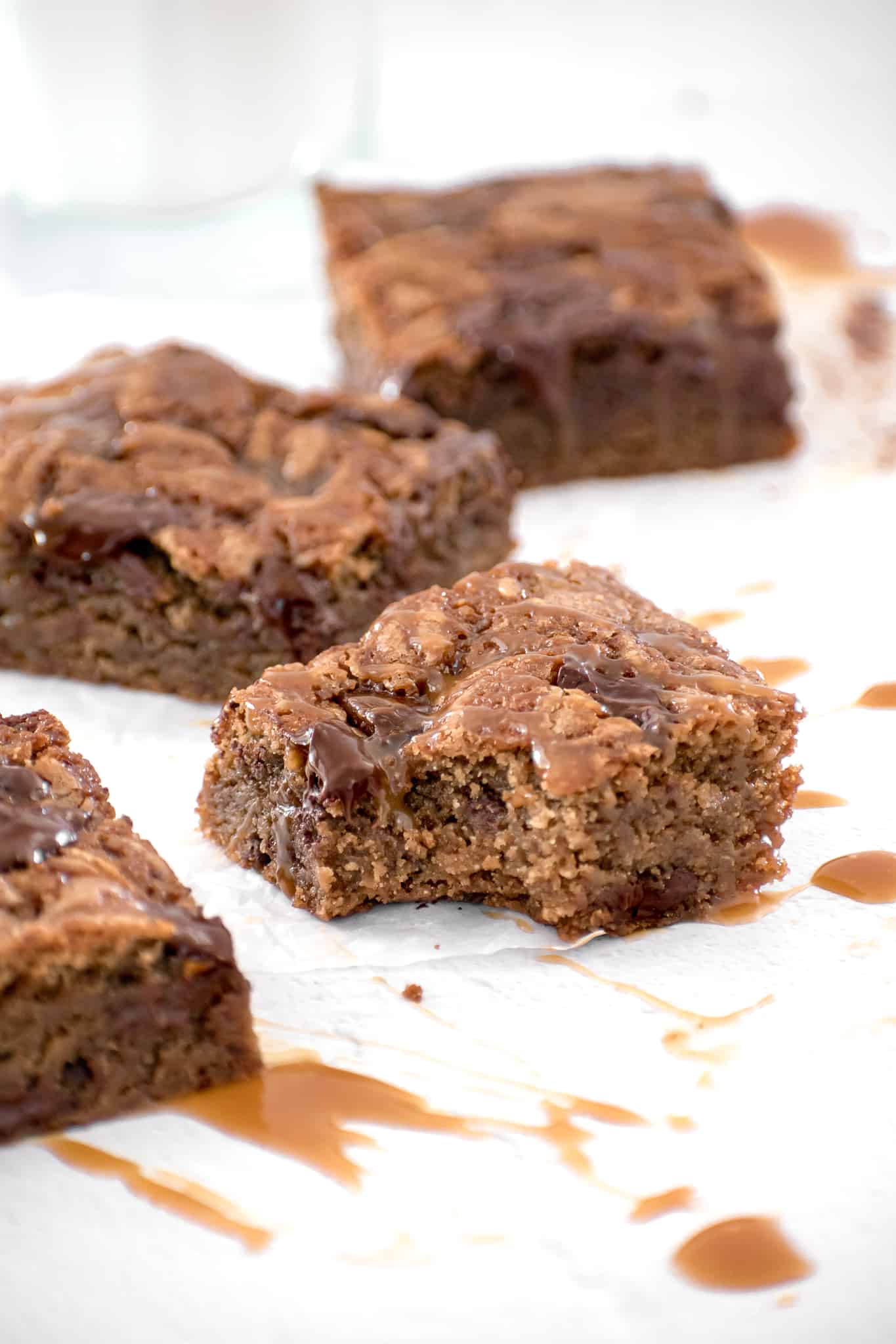 blondies on parchment paper with bite taken out of one.