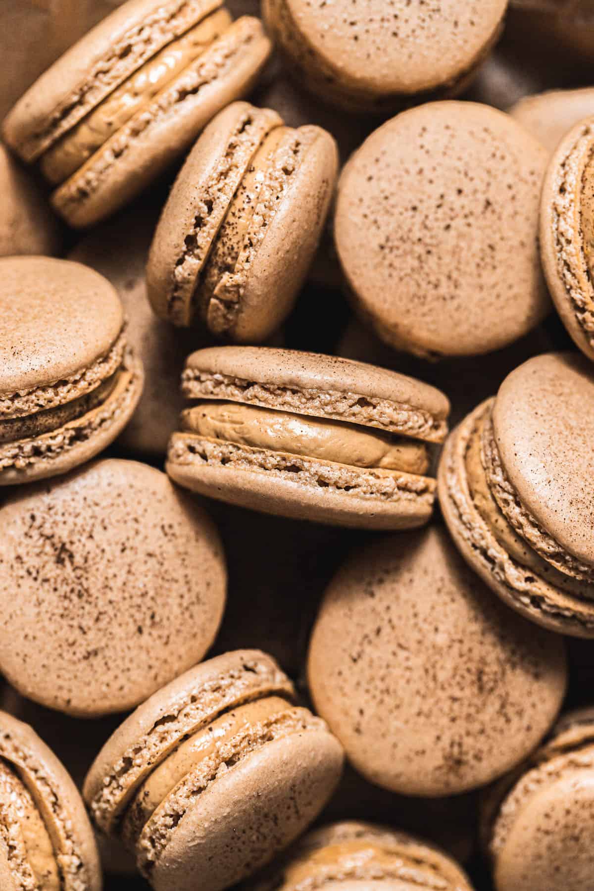 coffee macarons with french buttercream in a pile.