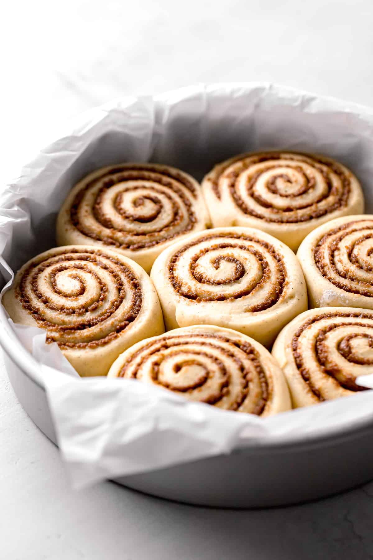 cardamom cinnamon rolls proofed in parchment lined cake pan.