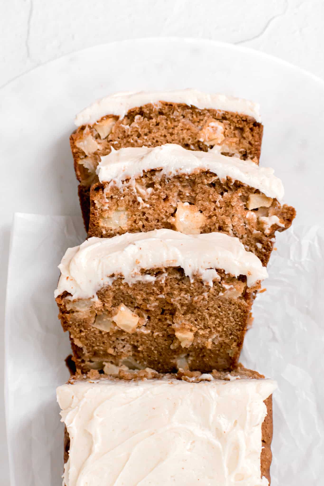 Apple Spice Loaf Cake with Brown Butter Cream Cheese Frosting sliced and stacked in a line.