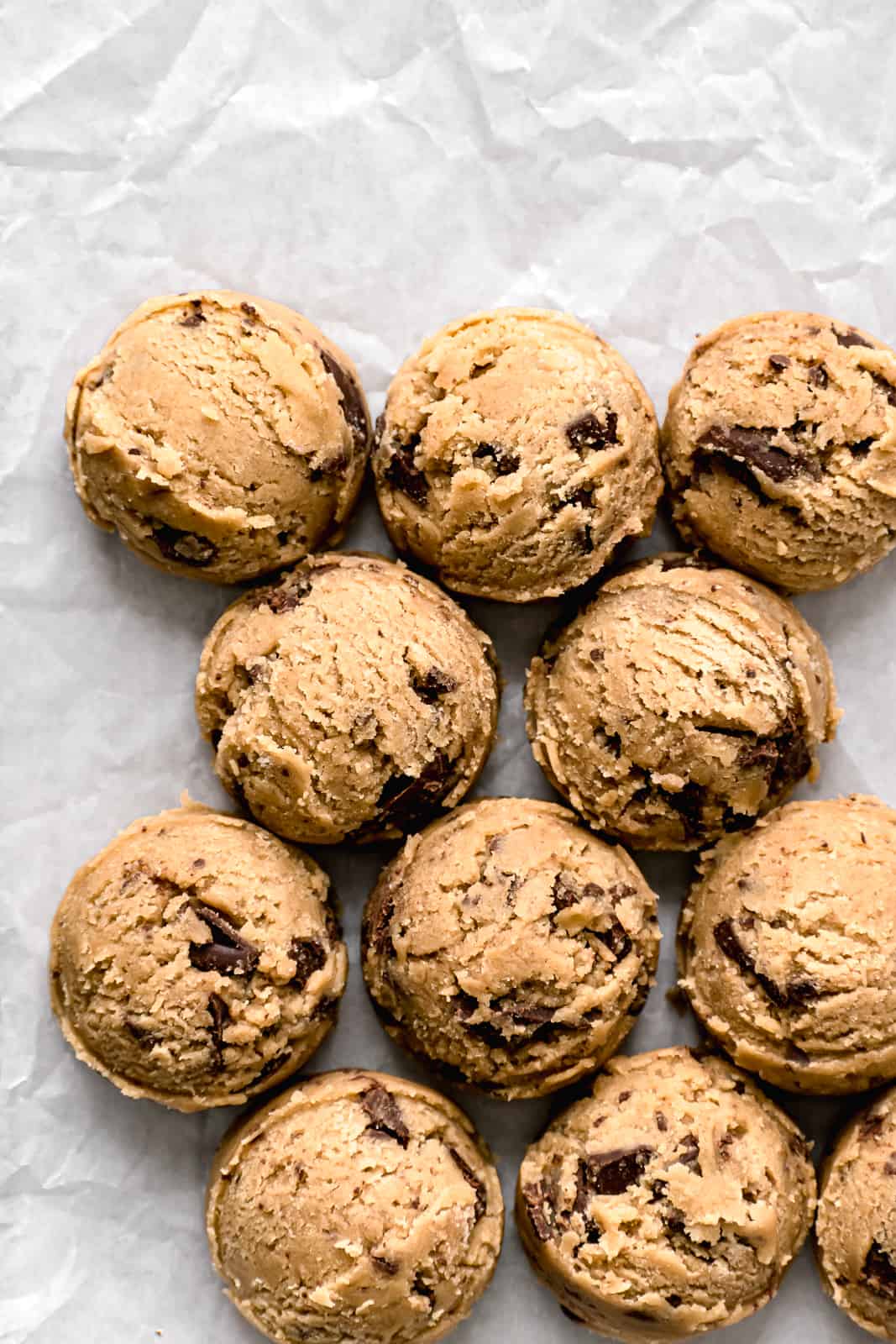 chocolate chip cookie dough balls on parchment lined baking sheet.