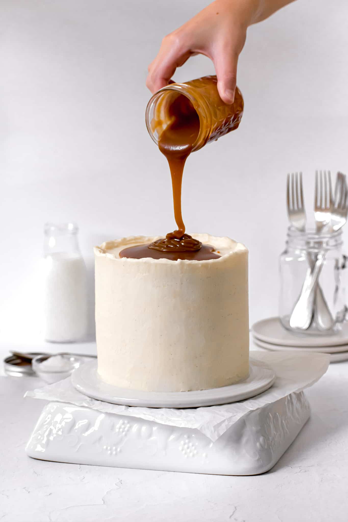 caramel layer cake with caramel sauce being poured on top.