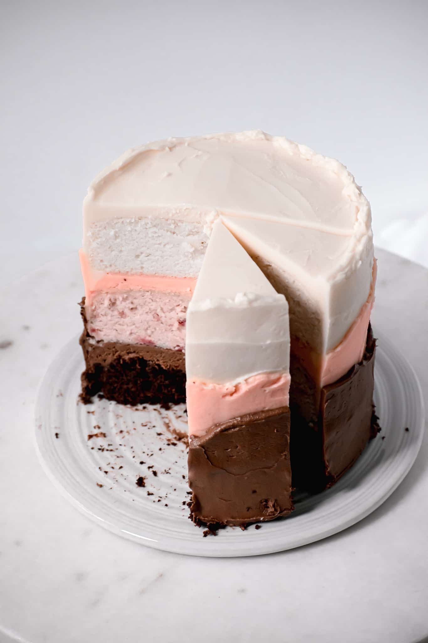 neapolitan cake with swiss meringue buttercream with slices taken out.