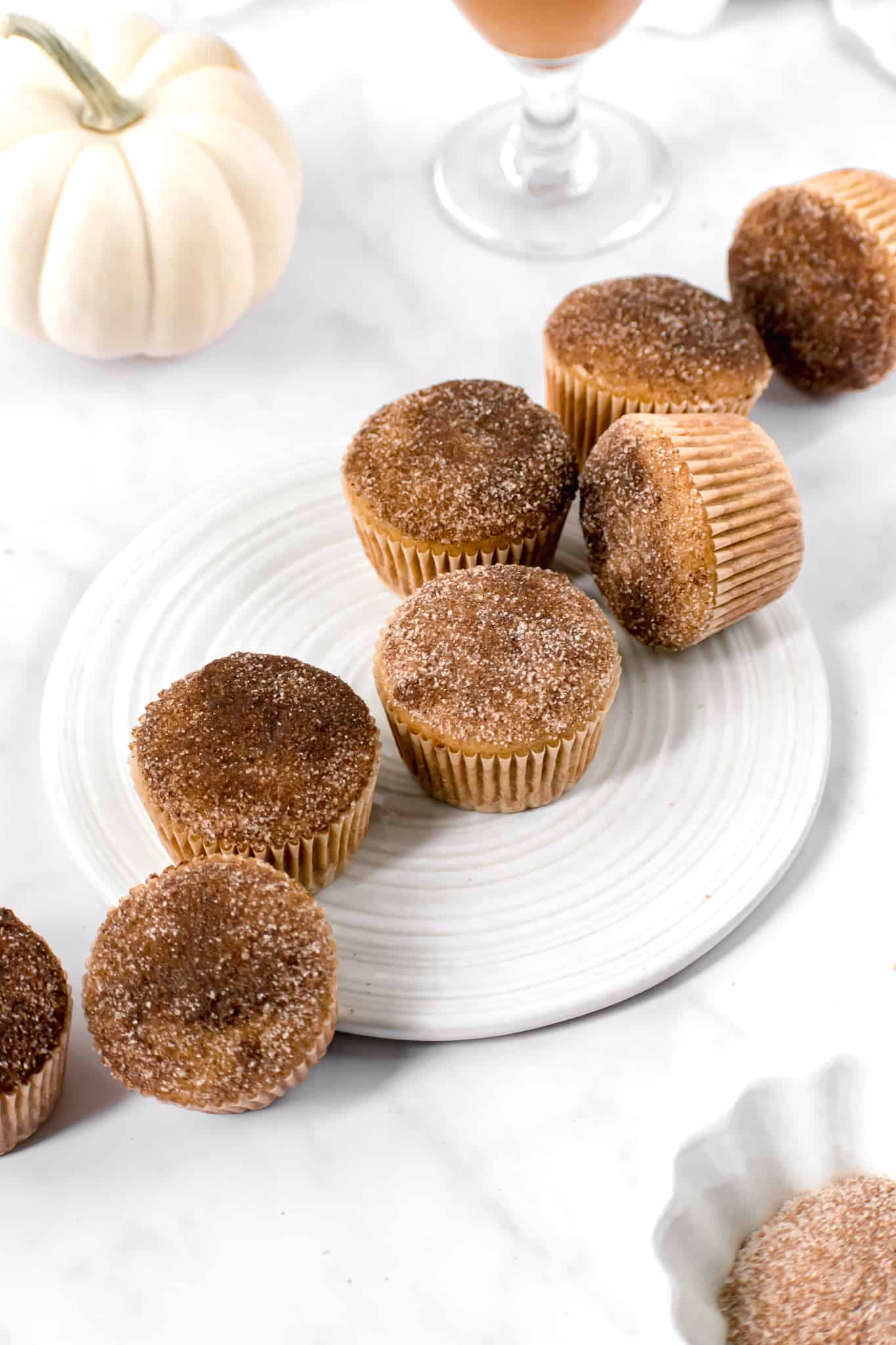 apple cider donut muffins scattered on a white plate.