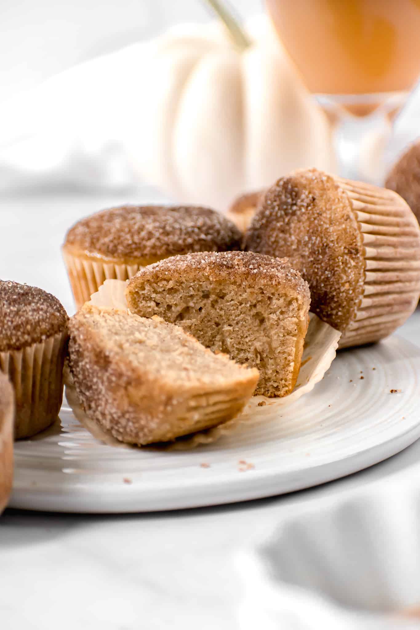 apple cider donut muffins on a plate with a slice through one muffin.