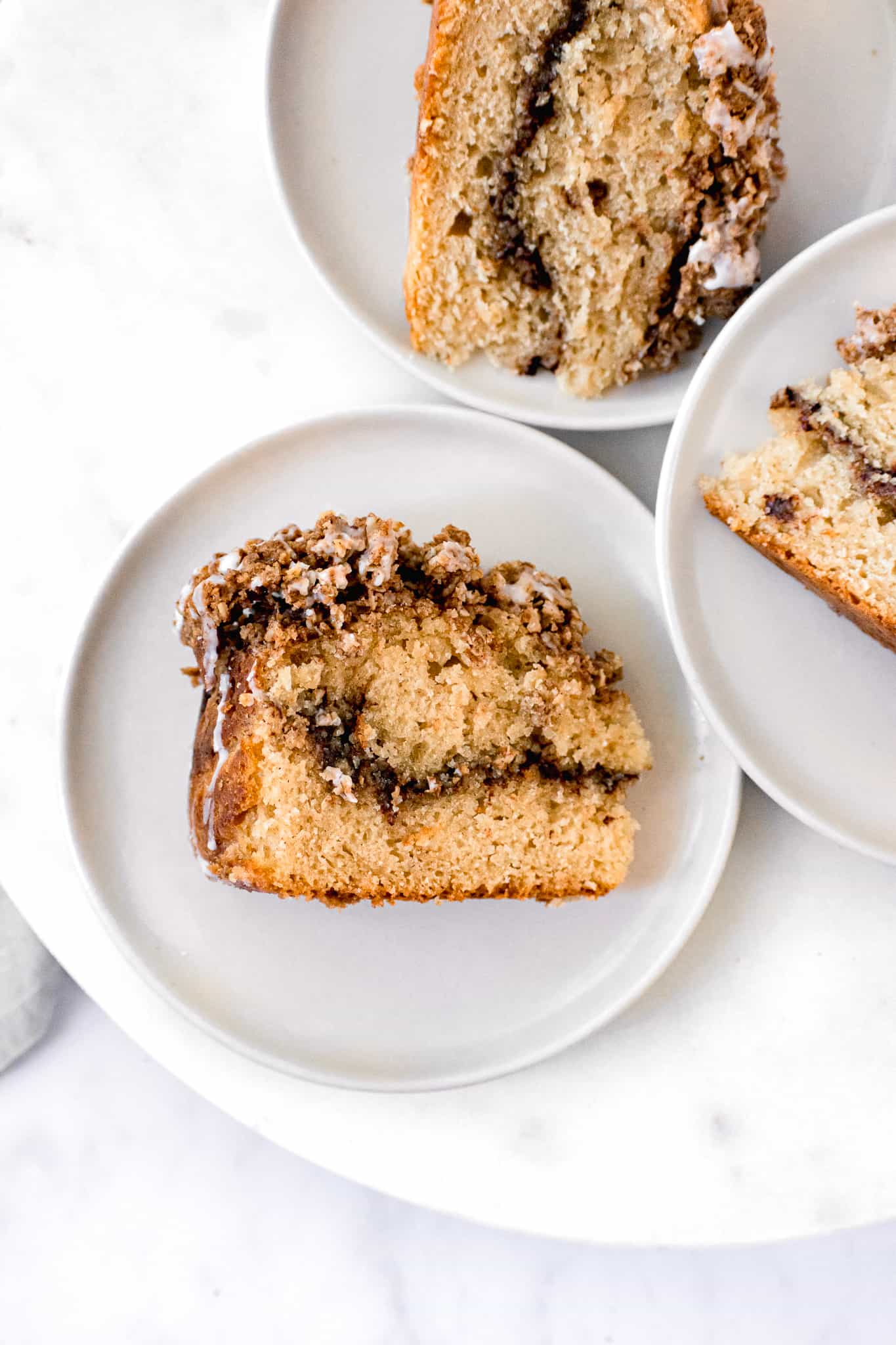 pieces of glazed chai streusel coffee cake on white plates.