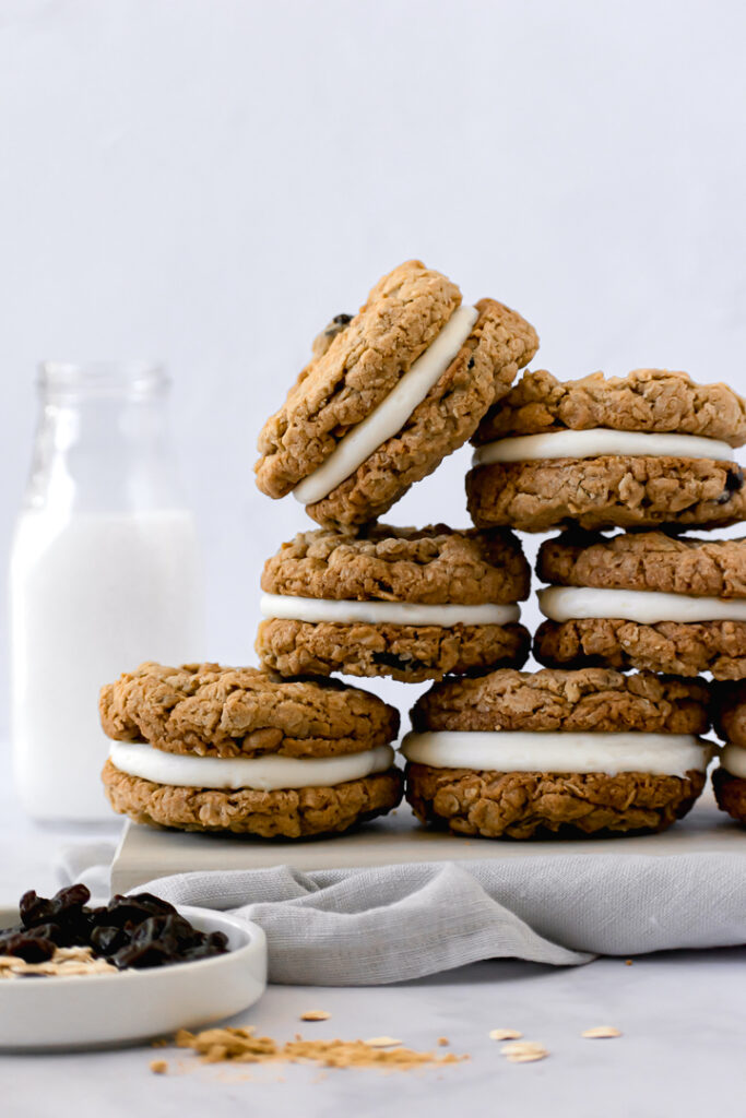 sandwich cookies stacked in a pyramid with a milk jar in the background 