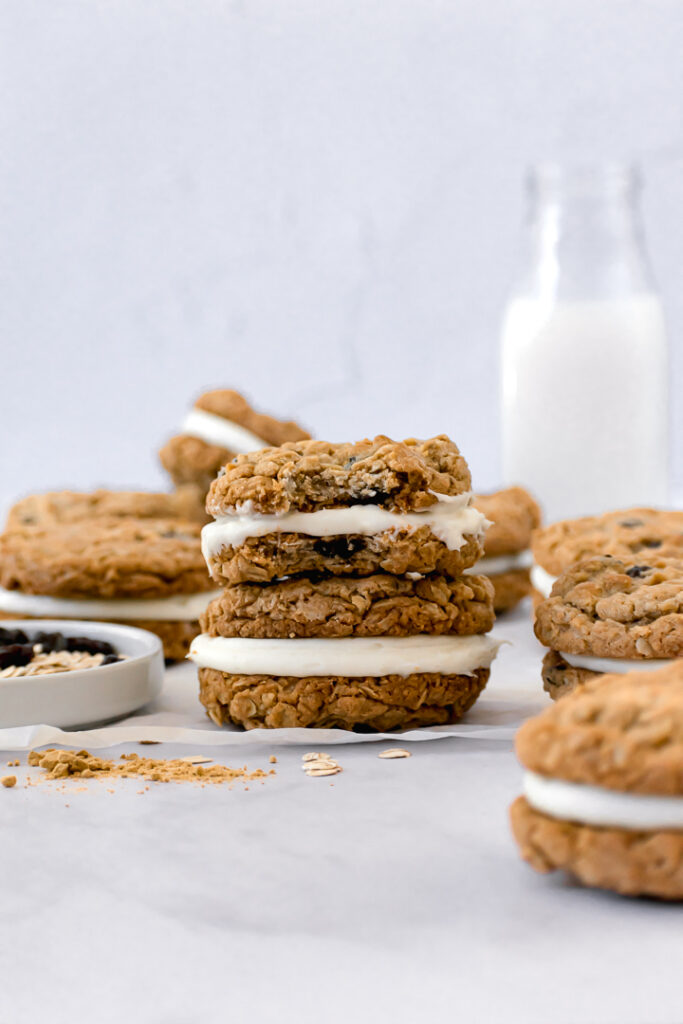two sandwich cookies stacked on top of each other with a milk jar in the background