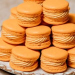 pumpkin macarons stacked on plate.