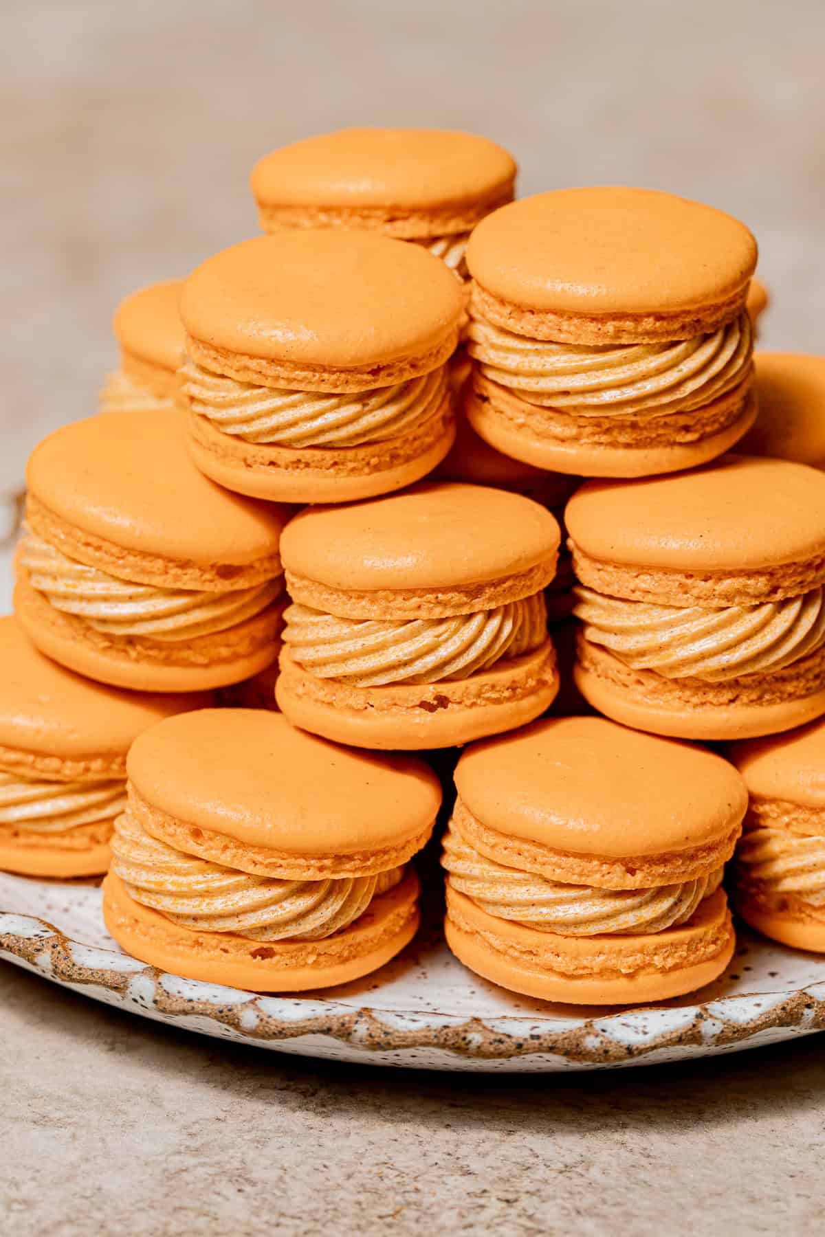 pumpkin macarons stacked on plate.