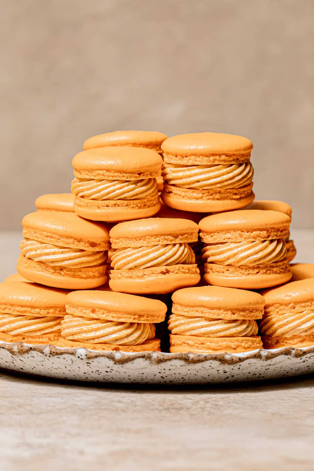 Pumpkin Macarons piled on plate.