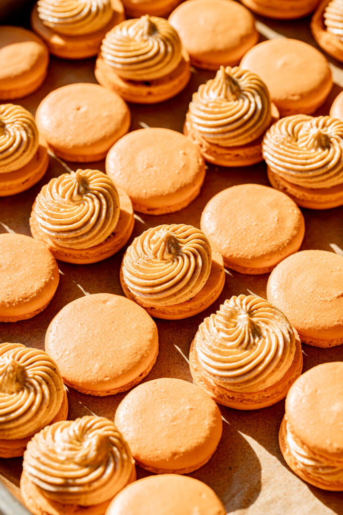 Pumpkin Macaron shells paired up and buttercream on bottom shells.