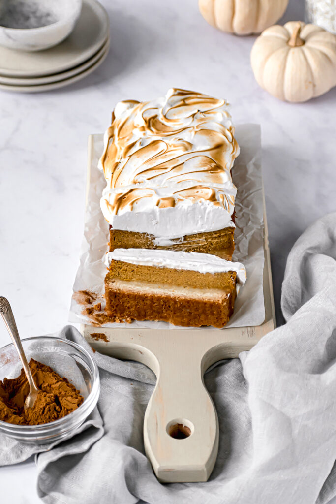 pumpkin pie bars on rectangular cutting board with mini pumpkins in the background
