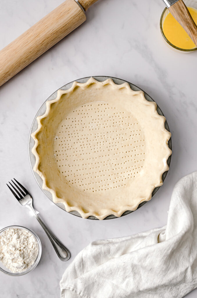 docked and crimped pie dough in metal pie pan
