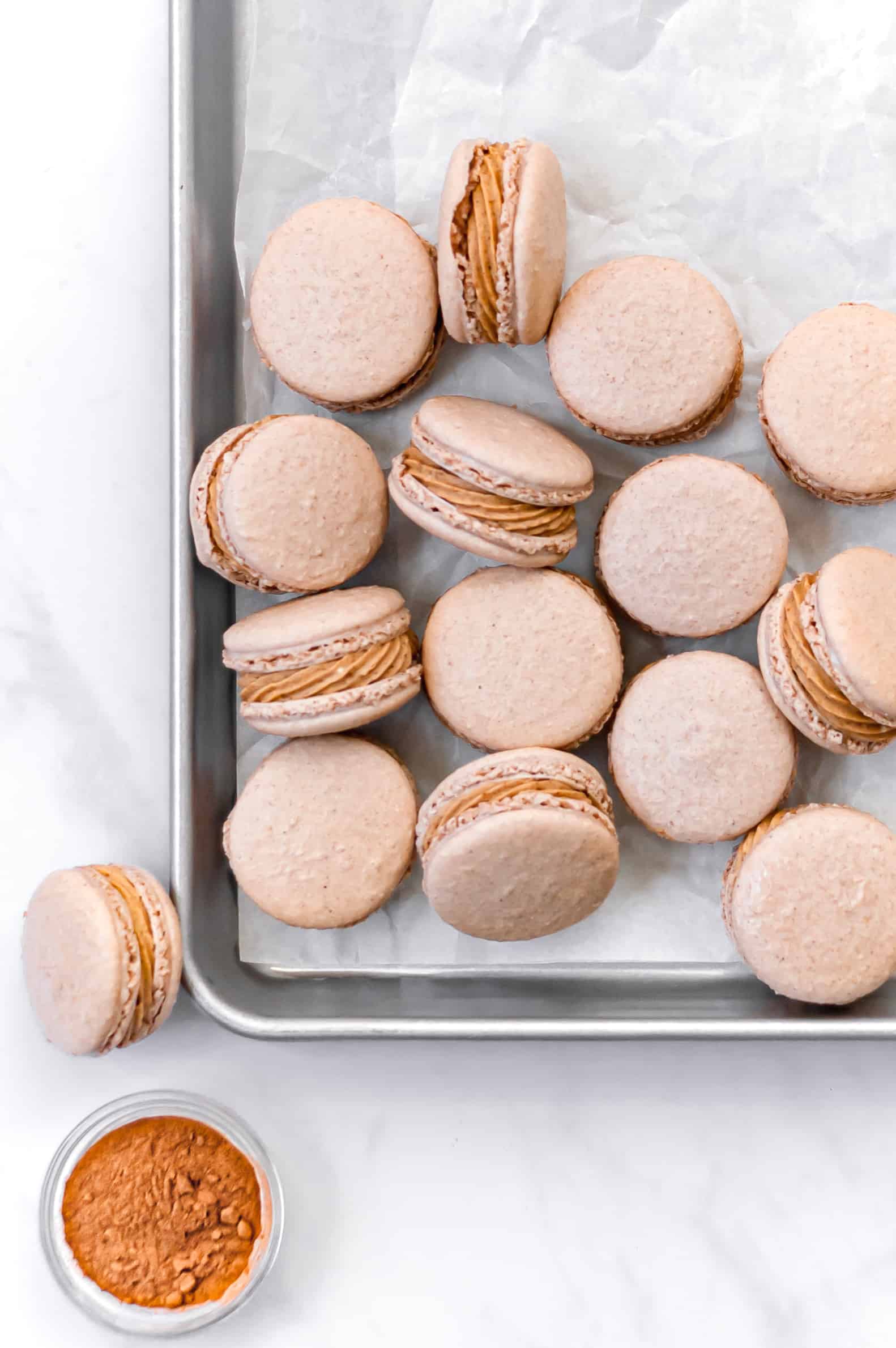 spiced macarons assembled on a baking tray with some resting on their sides.