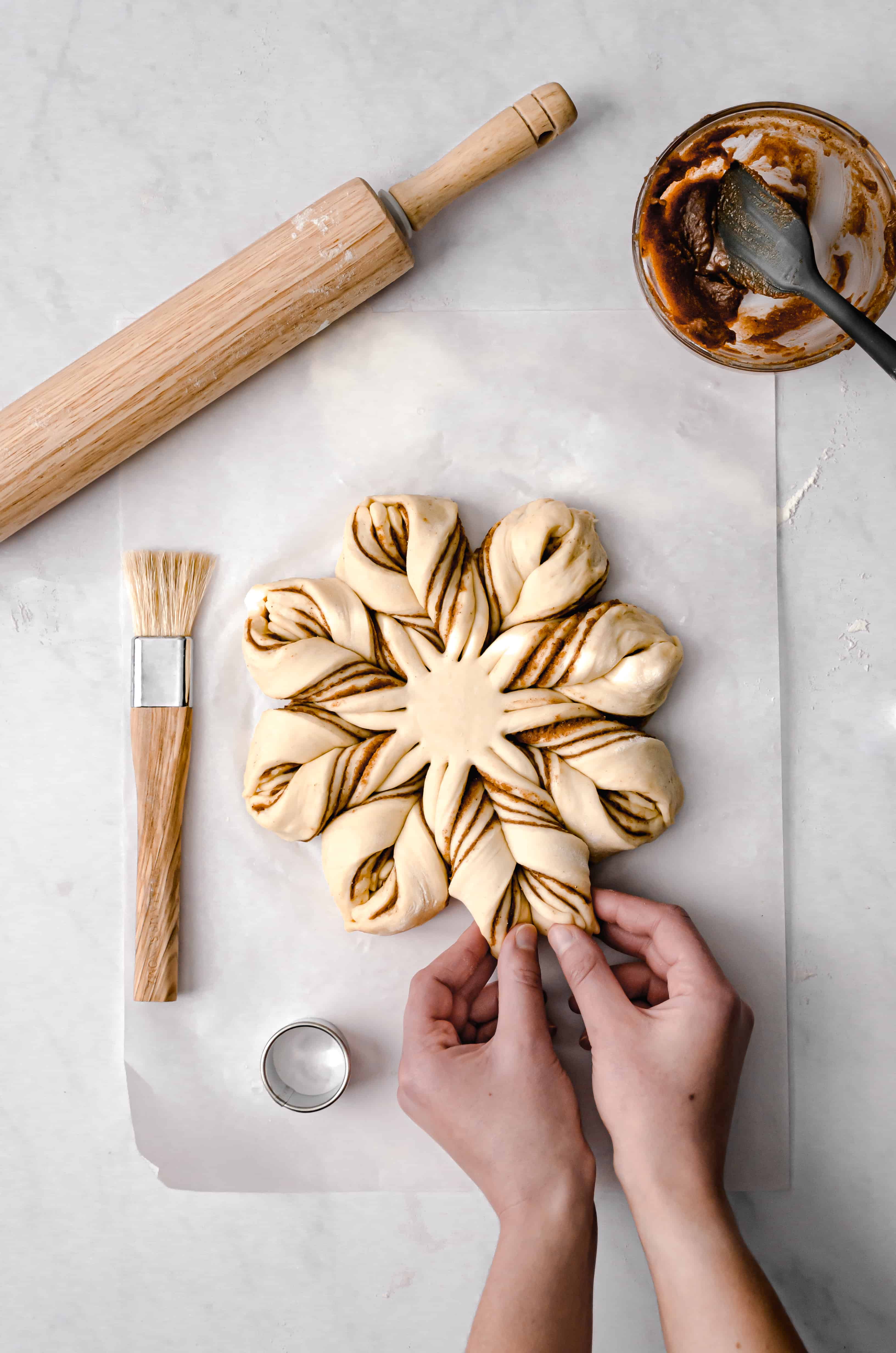 assembly of star bread with hands demonstrating how to shape it.