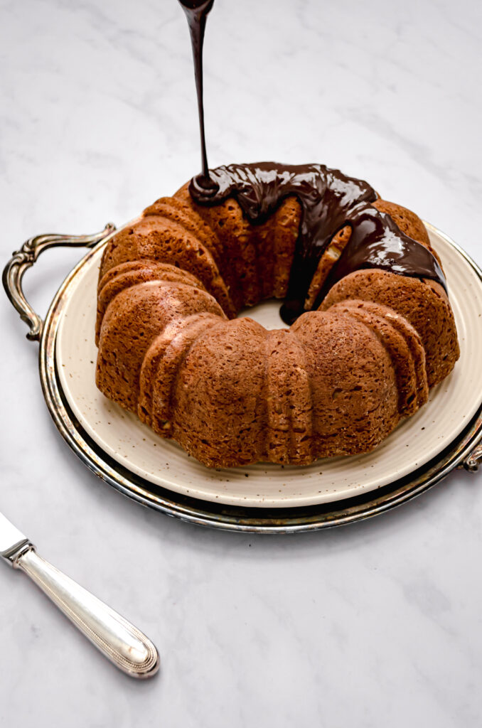 roasted banana bundt cake with chocolate glaze being drizzled on top