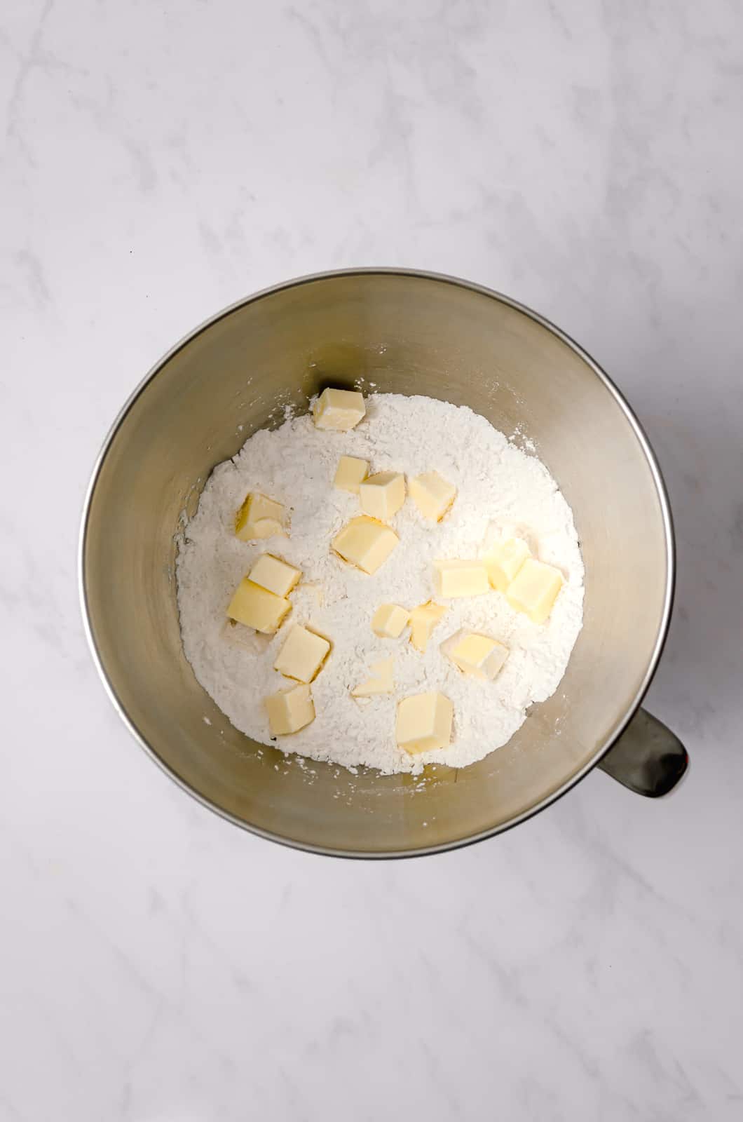 dry ingredients with cubes of butter for cake in large bowl.
