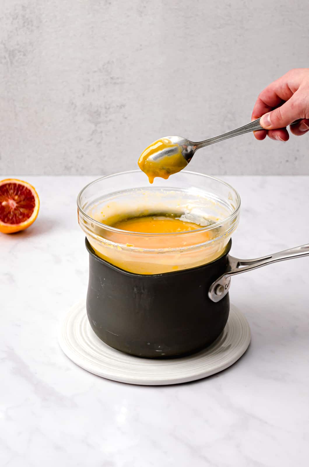 double boiler with blood orange curd and spoon.
