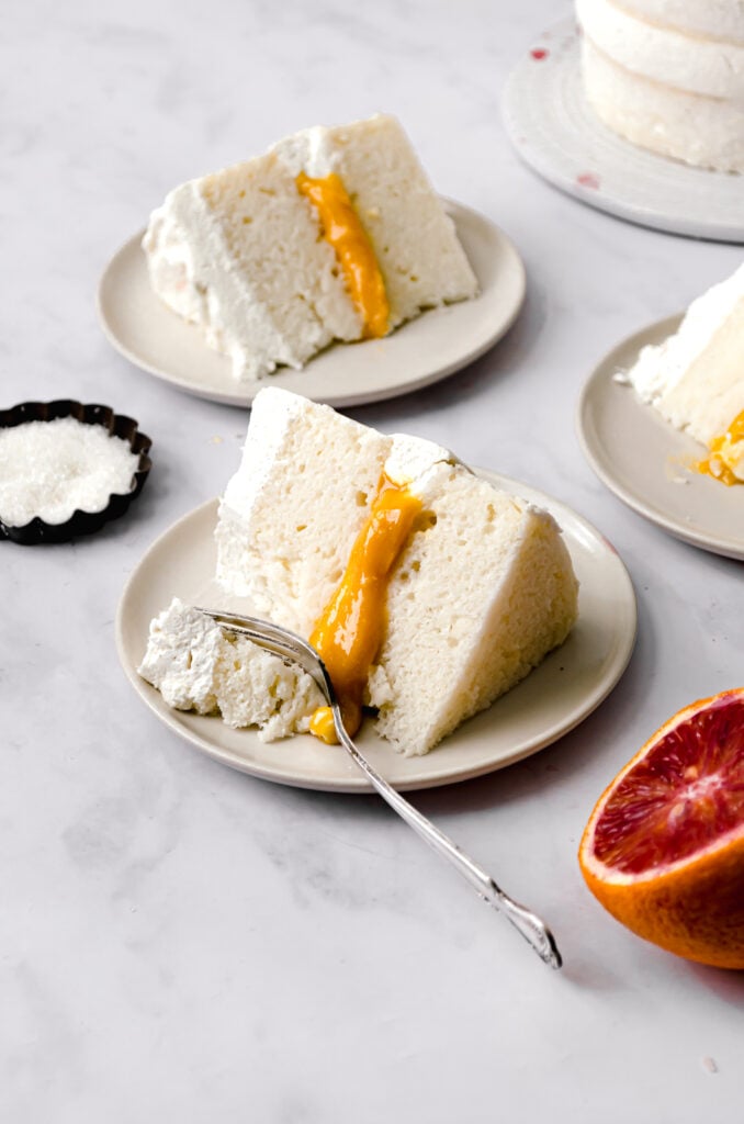 three slices of almond cake and blood orange curd with mascarpone frosting one three small plates