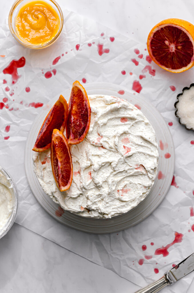 almond cake with blood orange curd and mascarpone frosting with blood orange slices on top  