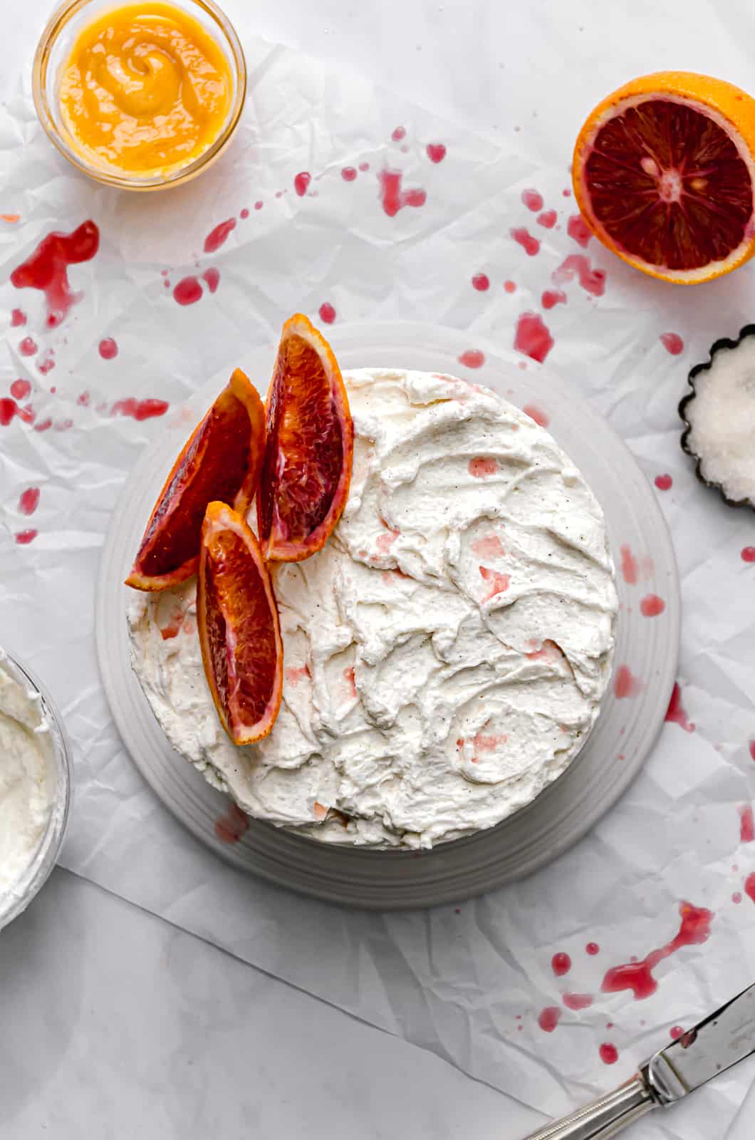 almond cake with blood orange curd and mascarpone frosting with blood orange slices on top.