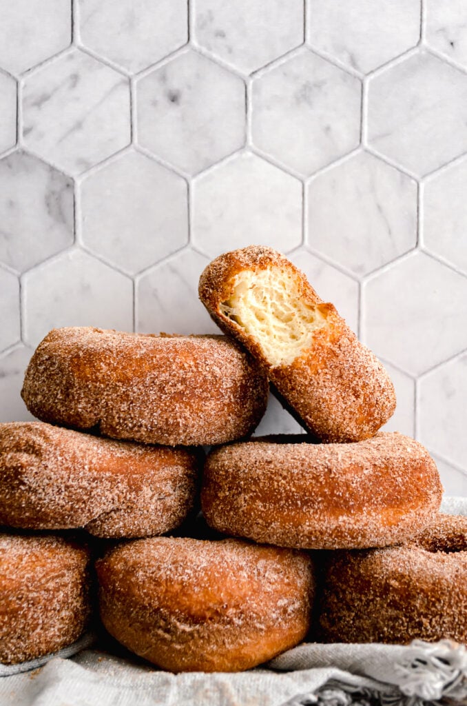 cinnamon sugar brioche donuts stacked up against marble tiled background 