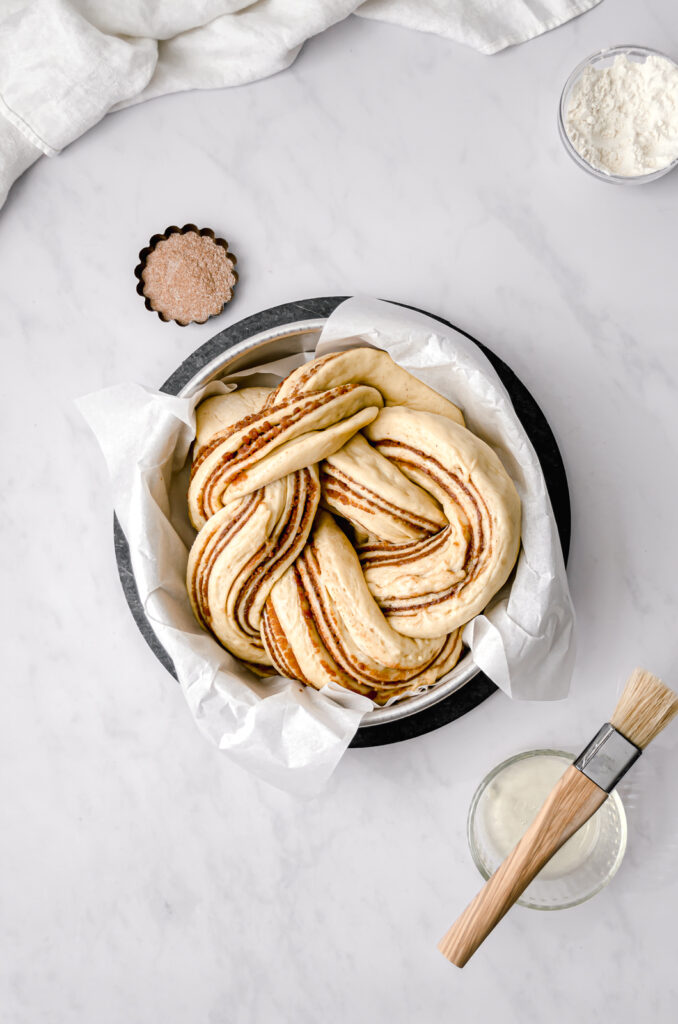 proofed cinnamon sugar brioche knot in parchment lined cake pan