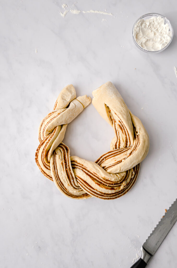 cinnamon sugar brioche knot being shaped on marble