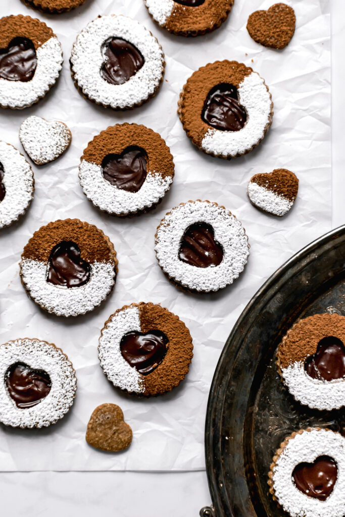 chocolate espresso linzer cookies with powdered sugar and cocoa powder on parchment paper
