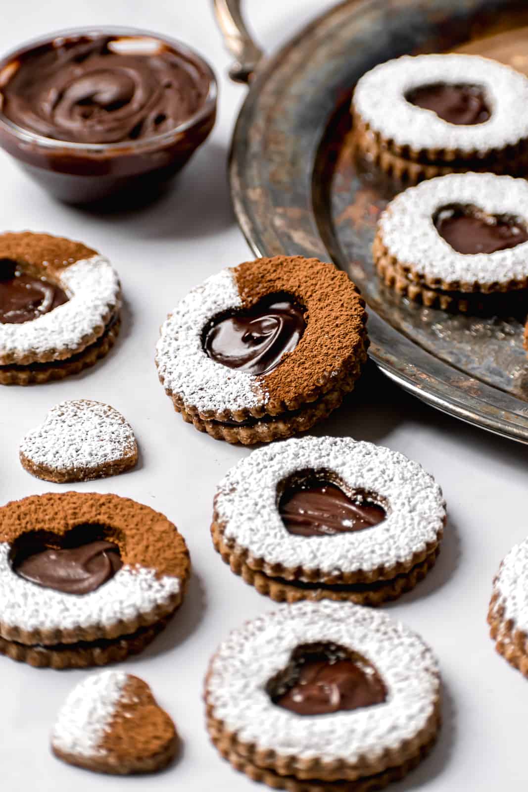 chocolate espresso linzer cookies with powdered sugar and cocoa powder on marble background.