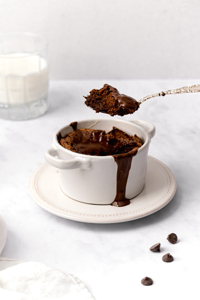 mini chocolate soufflé for one with melted chocolate on top and silver spoon held overhead 