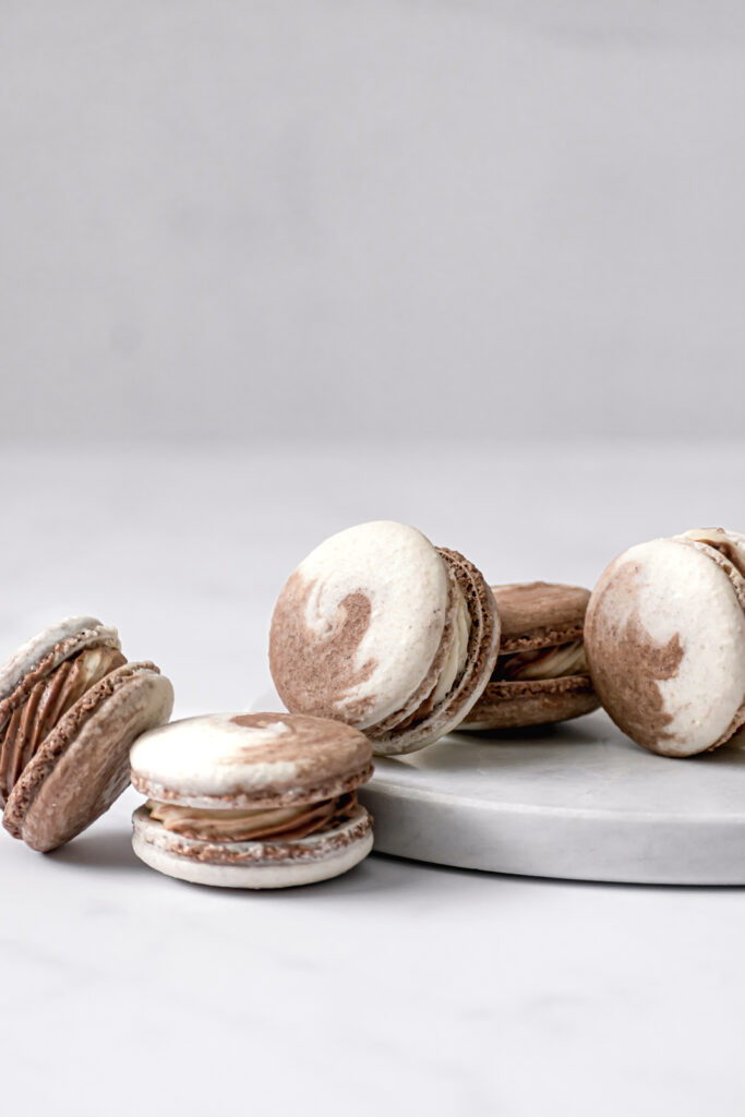 Chocolate & Vanilla Swirled Macarons leaned up against each other on marble