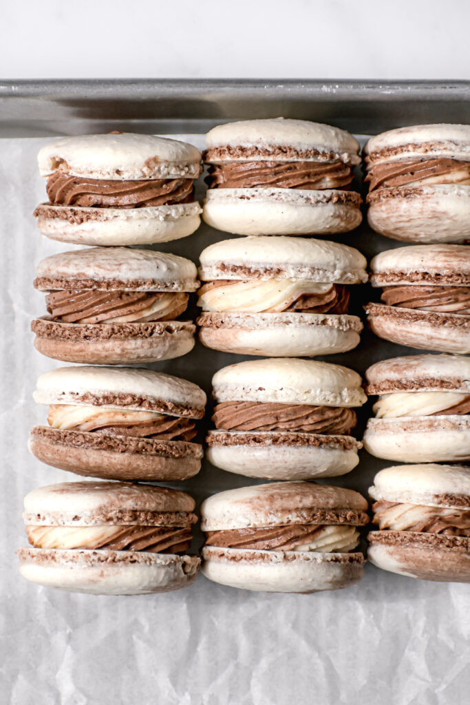 Chocolate & Vanilla Swirled Macarons lined up on parchment lined baking sheet