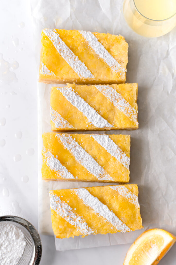 small batch lemon bars with an almond shortbread crust on parchment lined square marble board