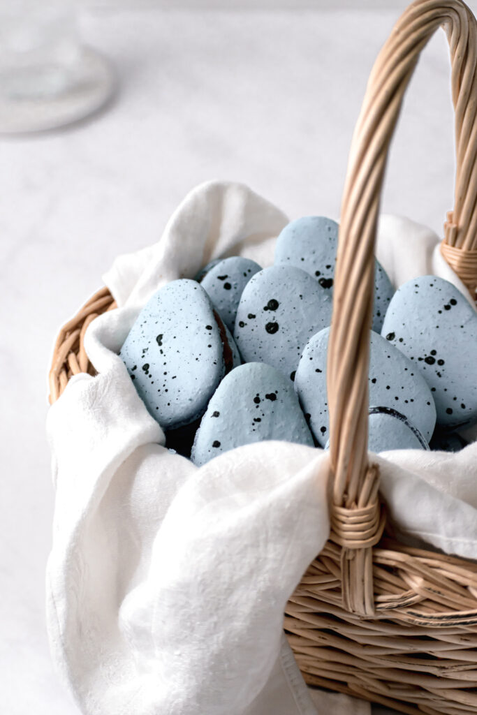 Robin's Egg Macarons with chocolate french buttercream in a basket lined with a white linen