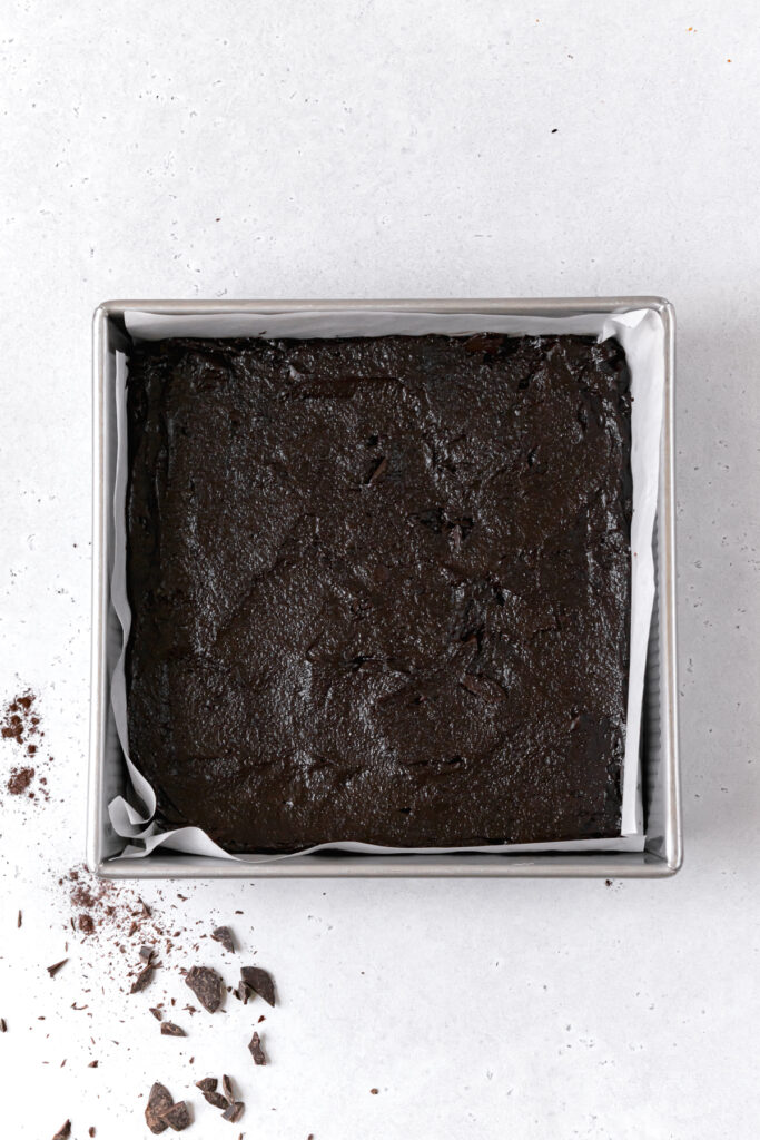 brownie batter in parchment lined metal square pan