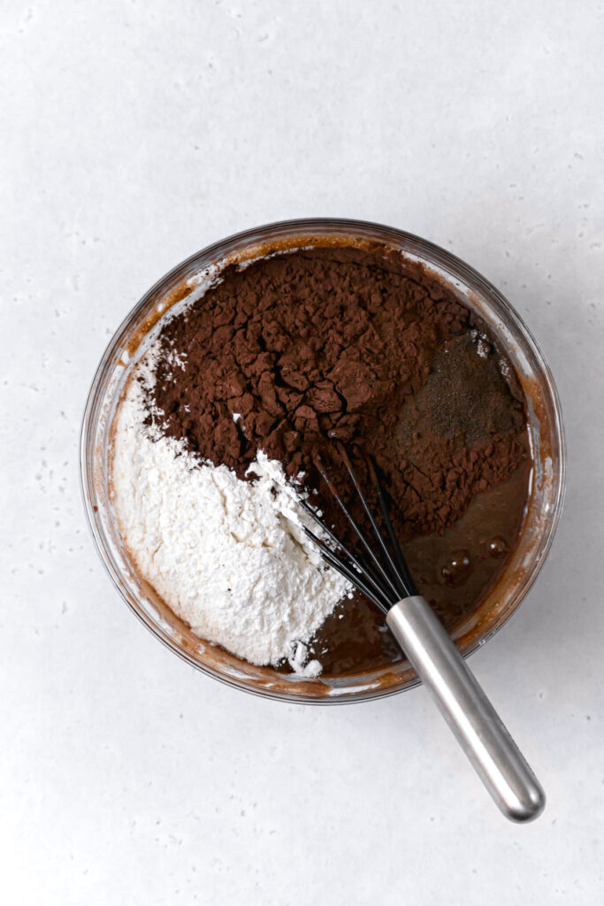 flour, dutch process cocoa powder, and espresso powder on top of wet ingredients in glass bowl