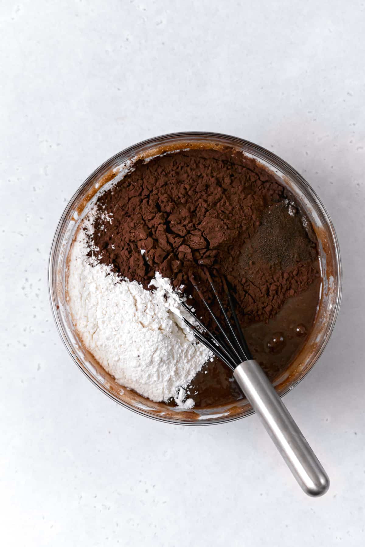 flour, dutch process cocoa powder, and espresso powder on top of wet ingredients in glass bowl.