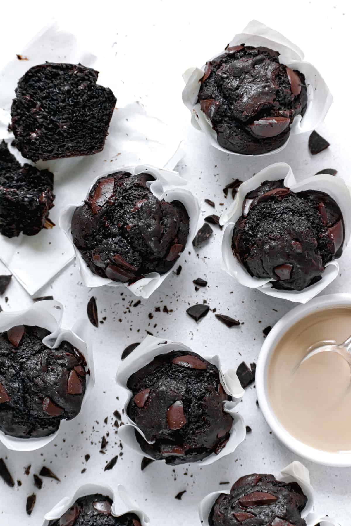 double chocolate tahini muffins with chopped chocolate everywhere and a bowl of tahini.