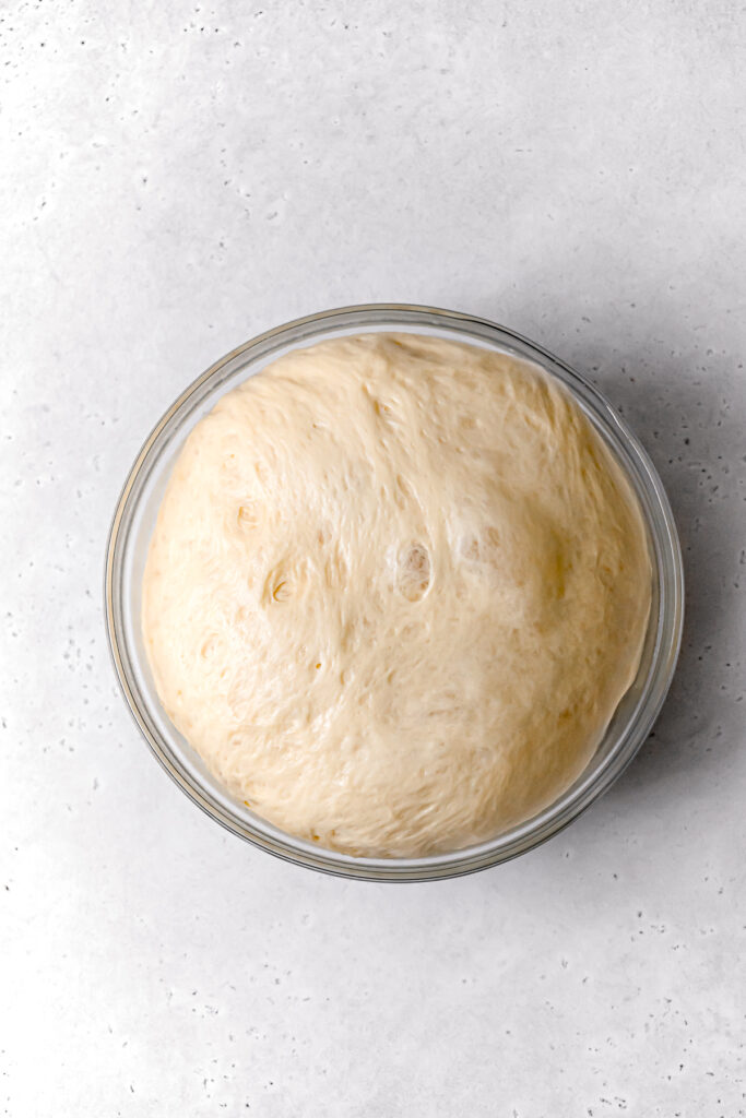 proofed brioche dough in glass bowl