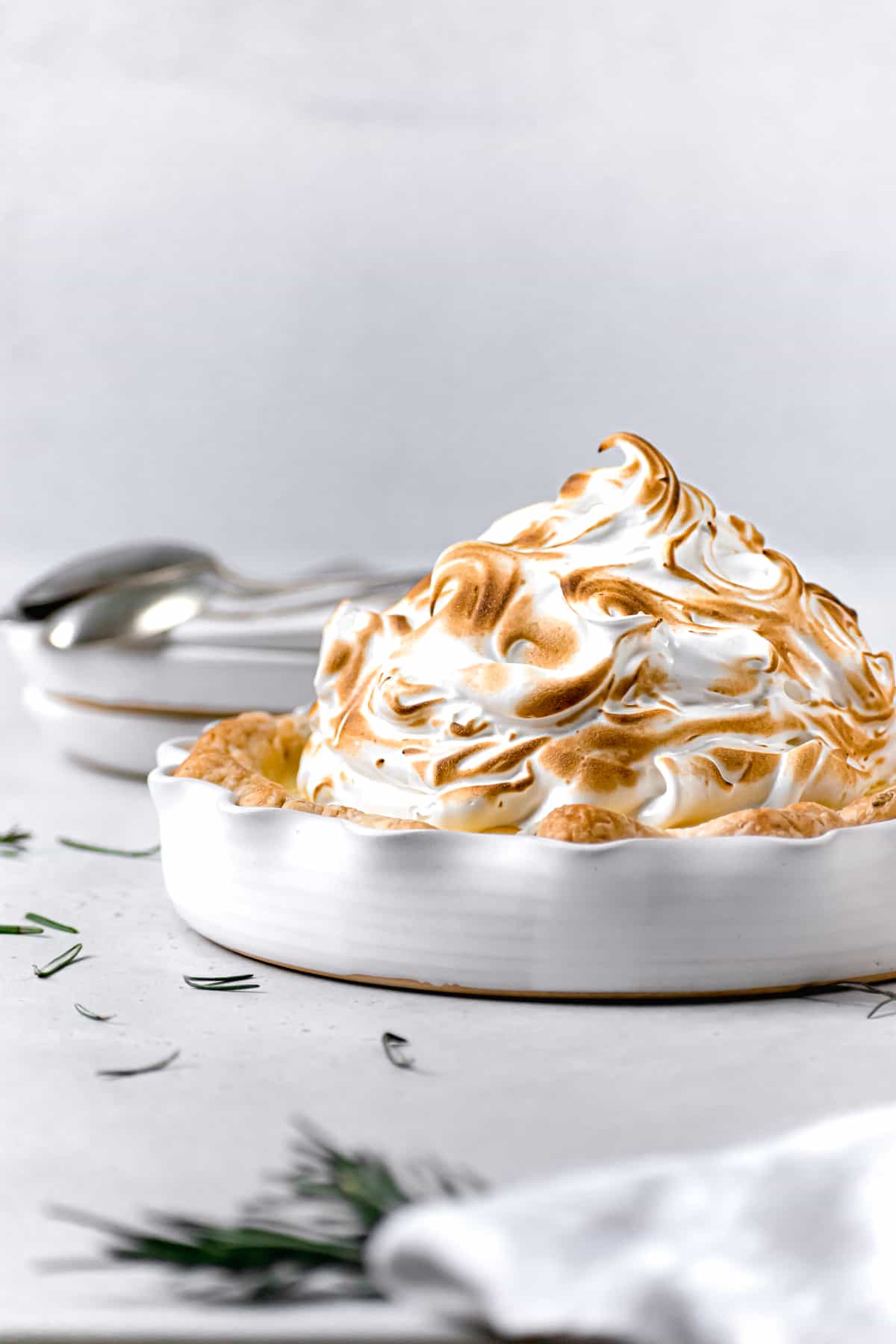lemon meringue pie in a white dish with toasted meringue on top.