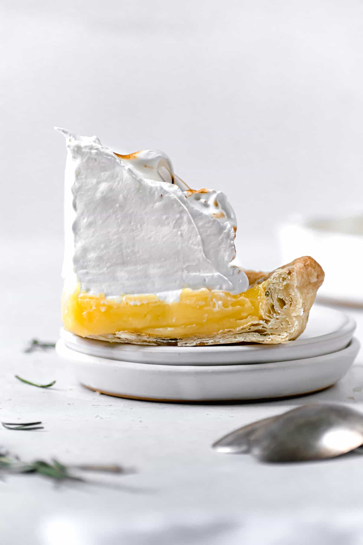 one piece of lemon rosemary meringue pie on white plate.