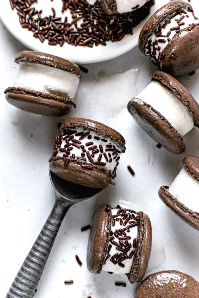 ice cream sandwiches some with chocolate jimmy sprinkles and a metal ice cream scoop