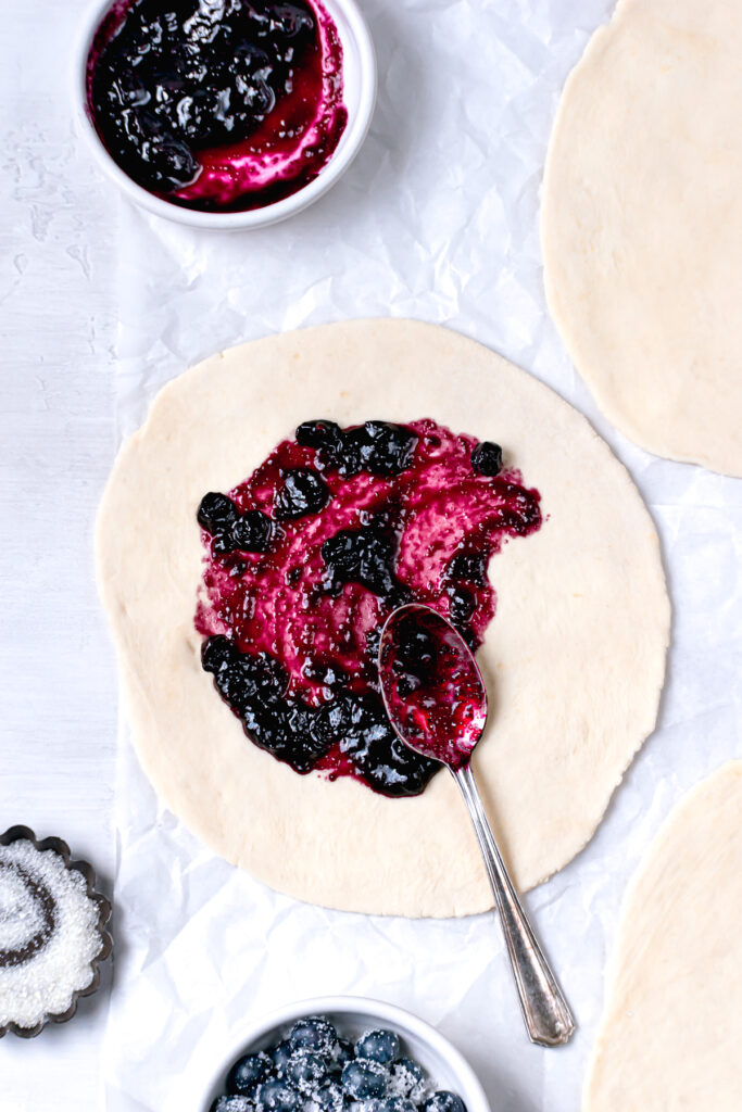 galette dough rolled out into three circles with jammy blueberry filling spread on top