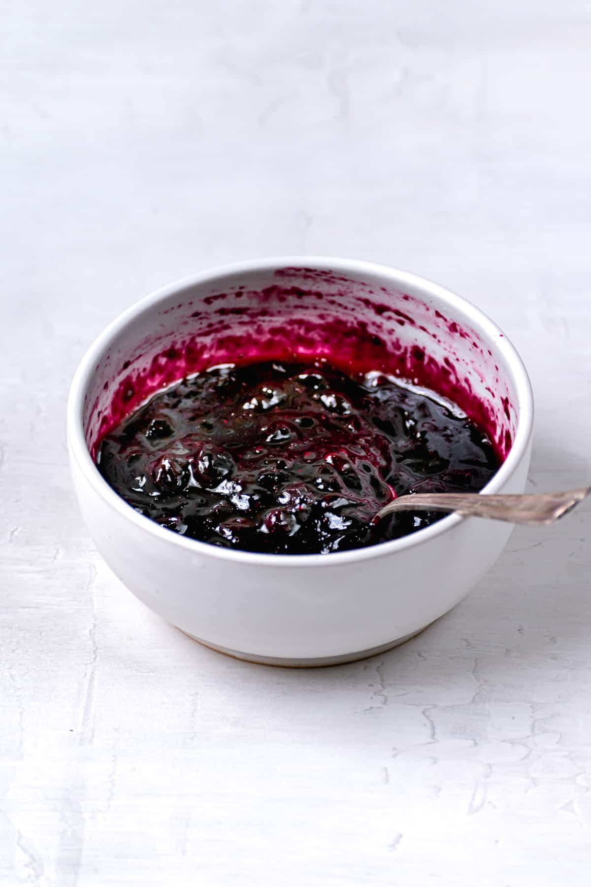 jammy blueberry filling in white bowl with spoon.