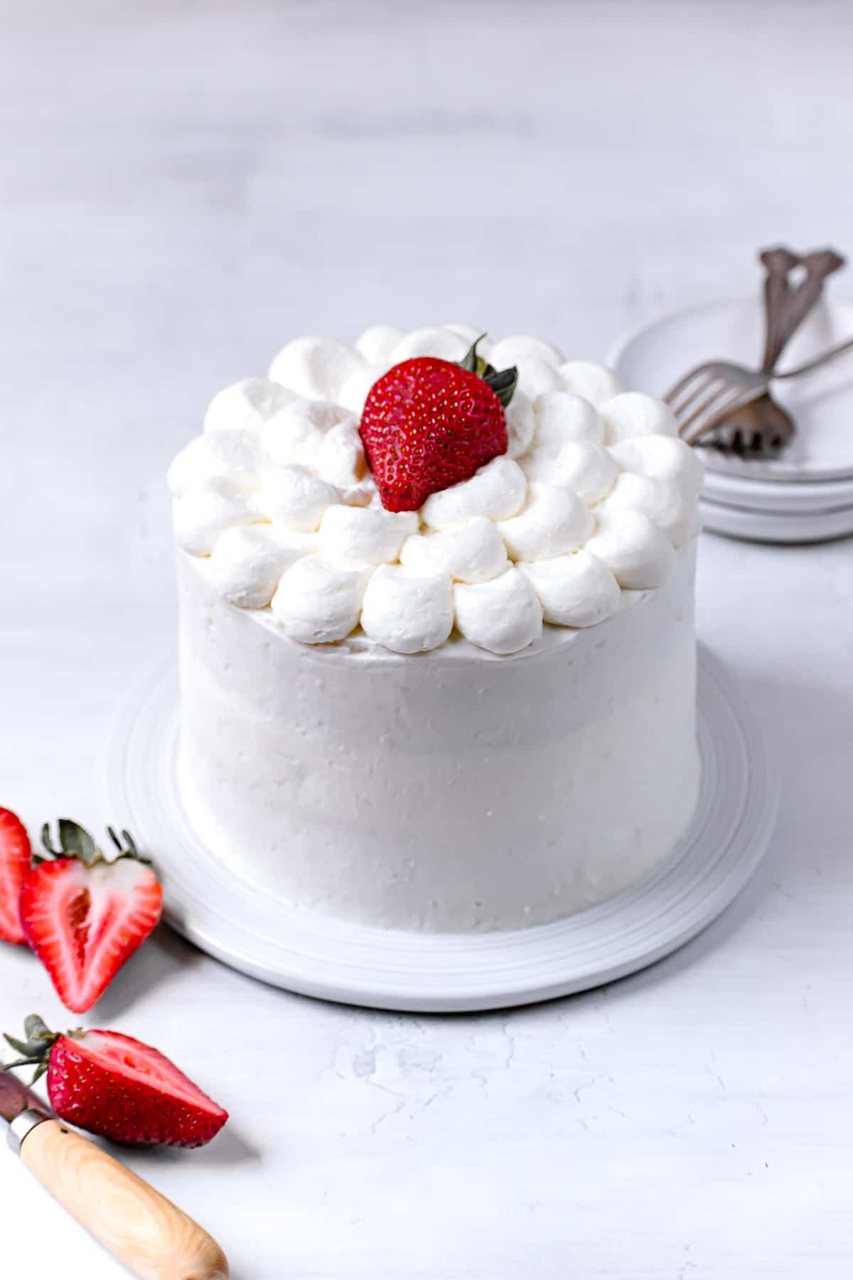 white cake with strawberries on white plate.